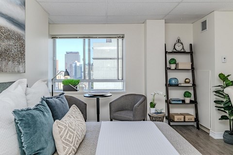 A well-lit bedroom with a large bed and a city view through the window.