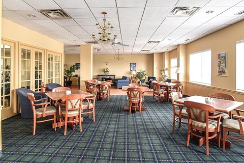 A large room with tables and chairs and a chandelier.
