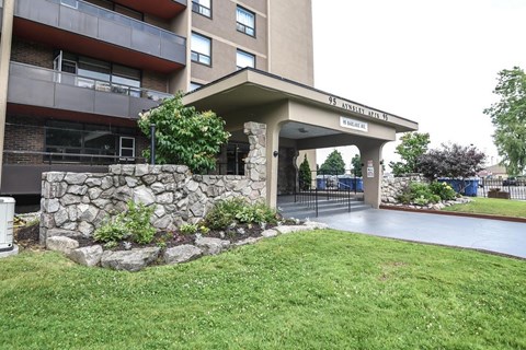 A stone wall and green grass surround a building entrance.