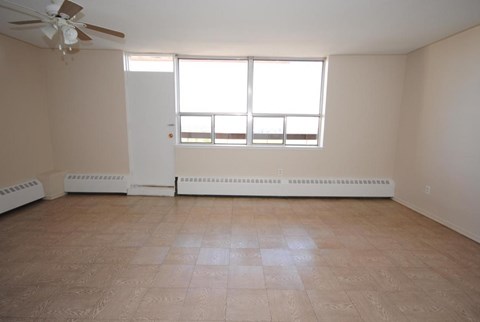 A room with a ceiling fan and a window with blinds.