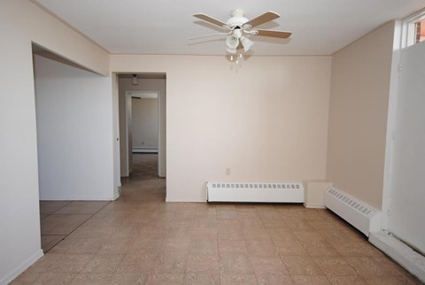 A room with a ceiling fan and a radiator on the wall.