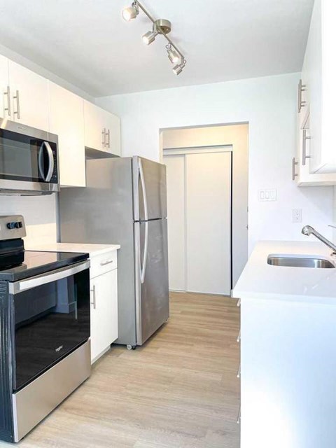 A kitchen with a stainless steel refrigerator, oven, and microwave.