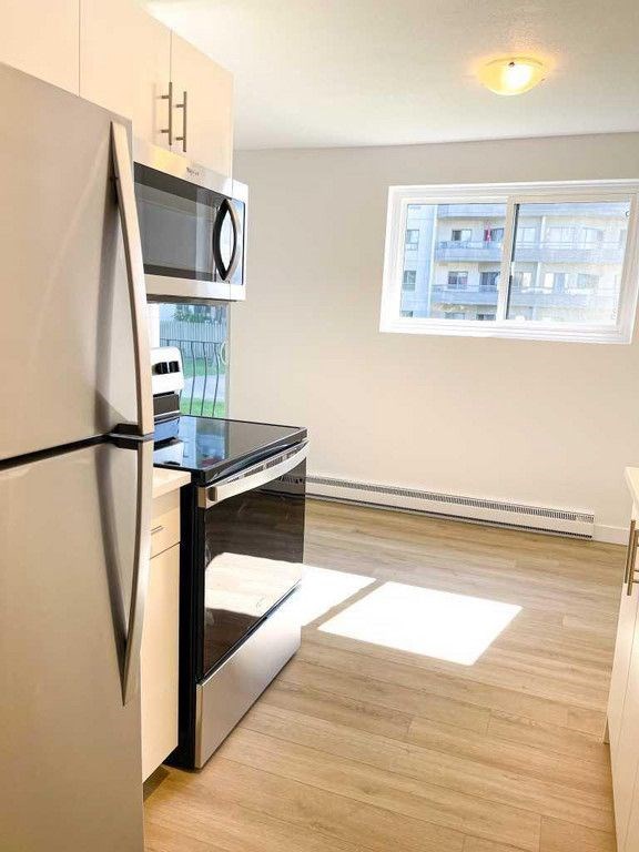 A kitchen with a refrigerator, microwave, and oven.