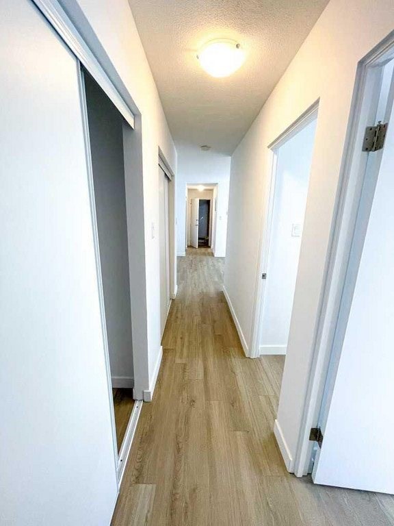A long hallway with white walls and wood flooring.