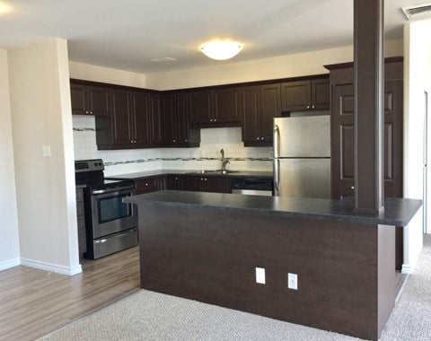 A kitchen with dark brown cabinets and a black oven.