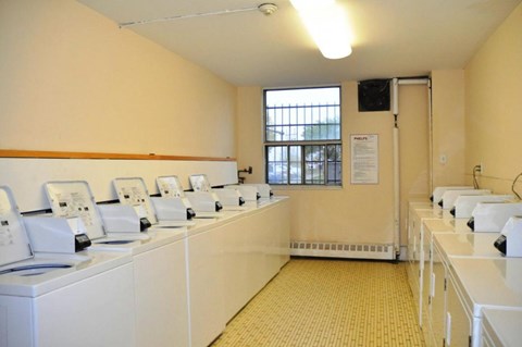 A row of white washing machines in a room with yellow walls.