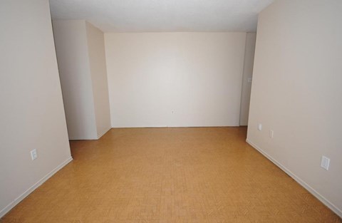 Empty room with light brown flooring and white walls.