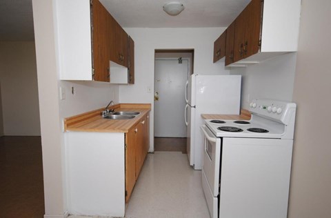 A small kitchen with white appliances and wooden cabinets.