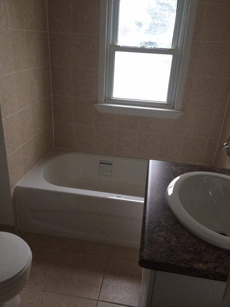 A white bathtub sits in a bathroom next to a toilet and a sink.