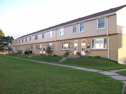 A long building with a green lawn in front.
