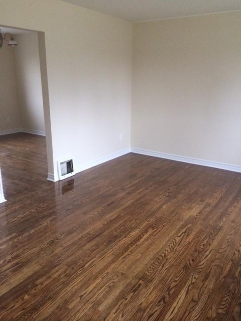 A room with wooden flooring and a white wall.
