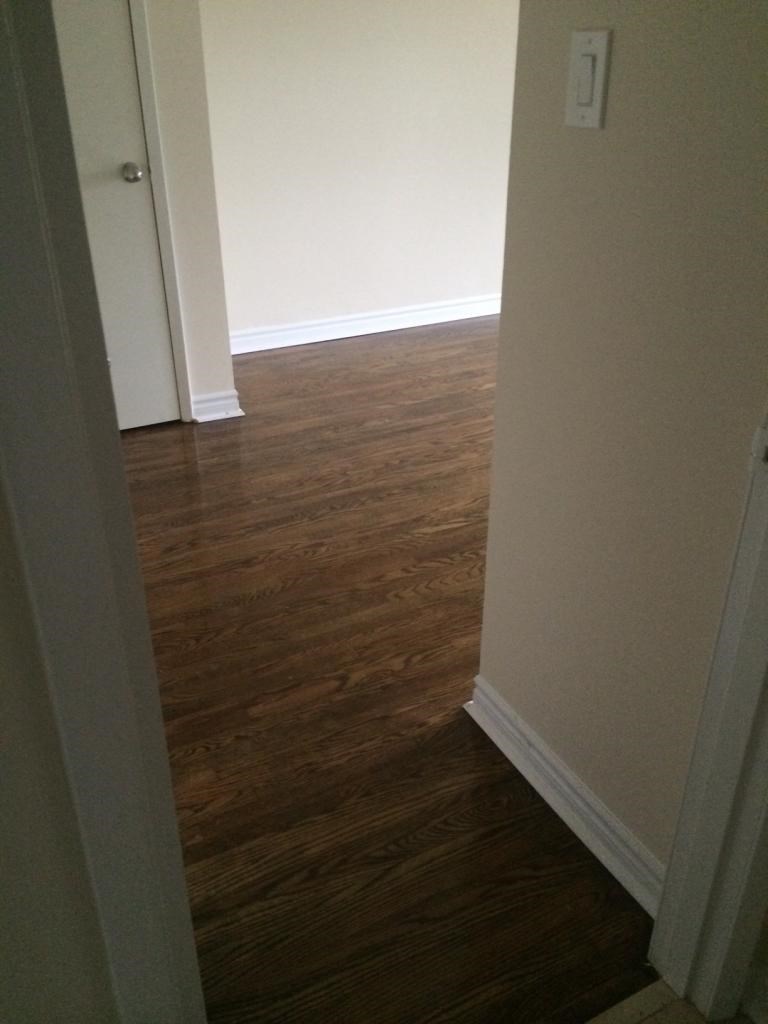 A hallway with wood floors and white walls.