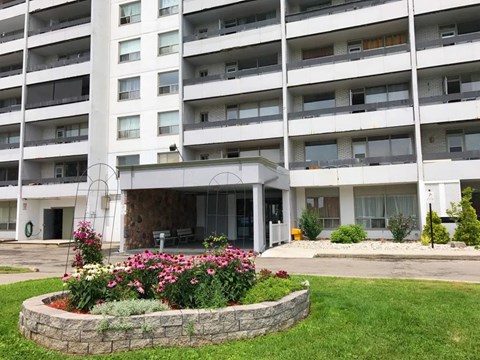 A large white building with a flower bed in front.