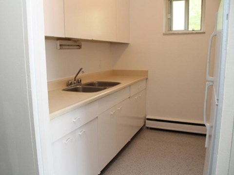 A kitchen with white cabinets and a window.
