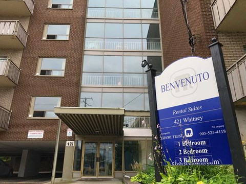 A sign for Benvenuto Rental Suites stands in front of a building.