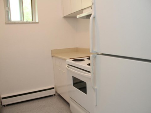 A white kitchen with a stove and refrigerator.