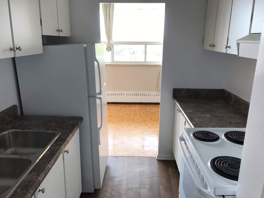 A kitchen with a stove, sink, and cabinets.