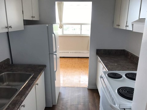 A kitchen with a stove, sink, and cabinets.