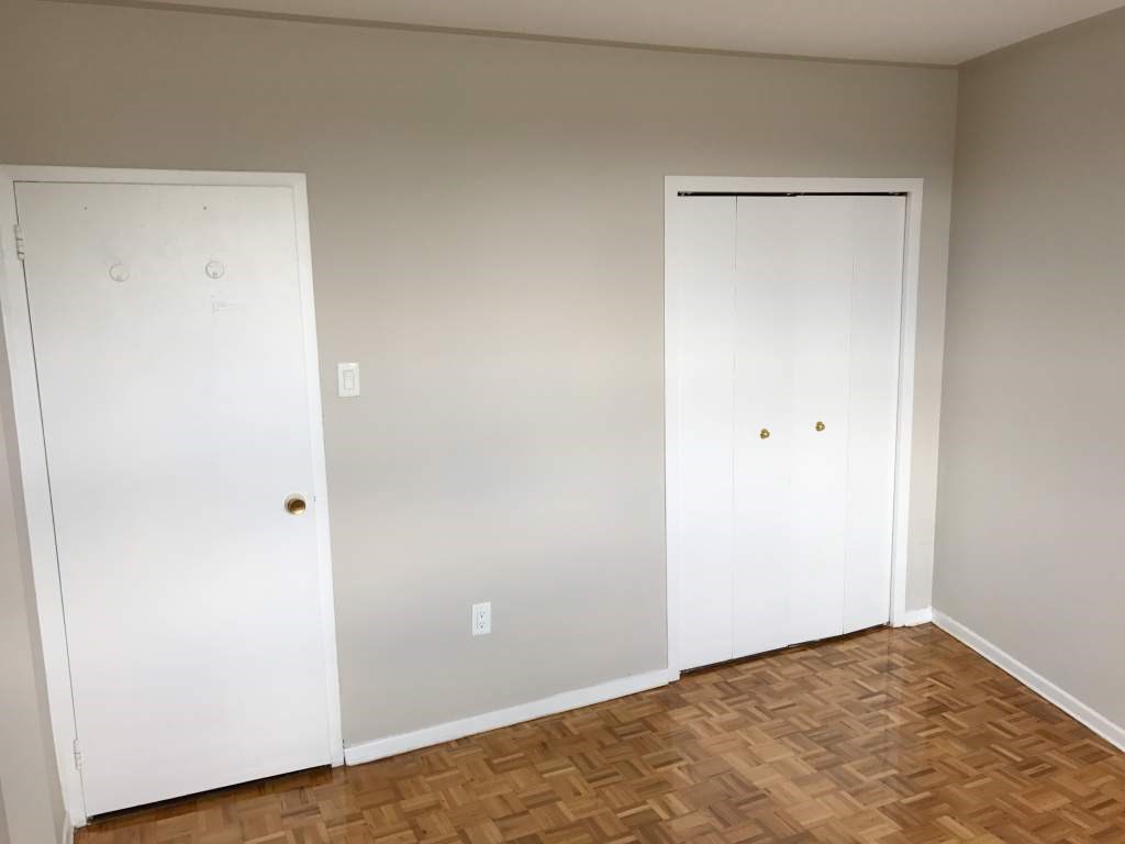 A room with two white doors and wooden flooring.