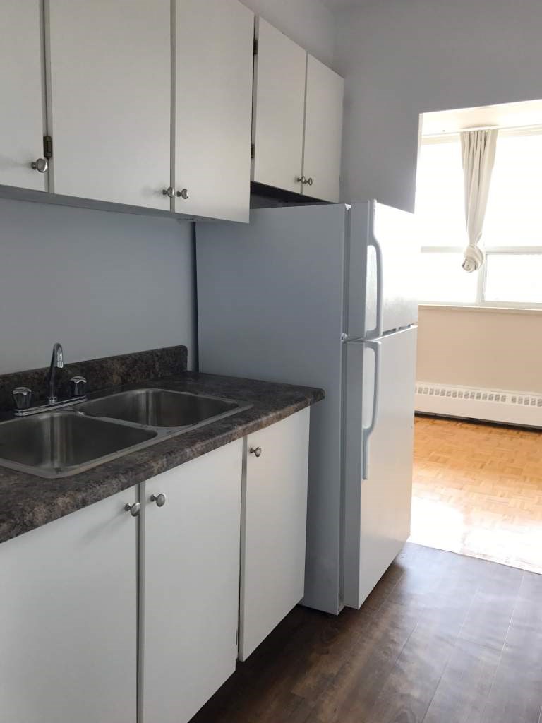 A kitchen with white cabinets and a grey counter top.