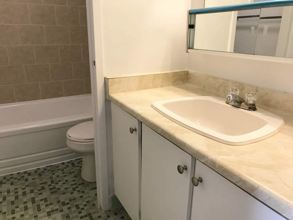 A white bathroom with a sink, toilet and bathtub.