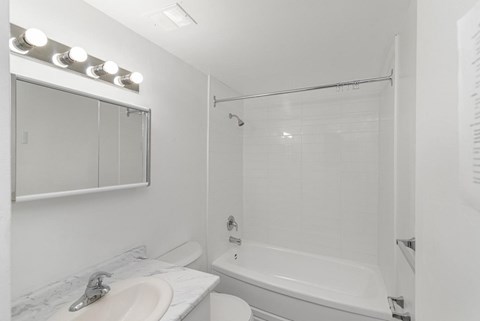 A white bathroom with a sink, mirror, and shower.