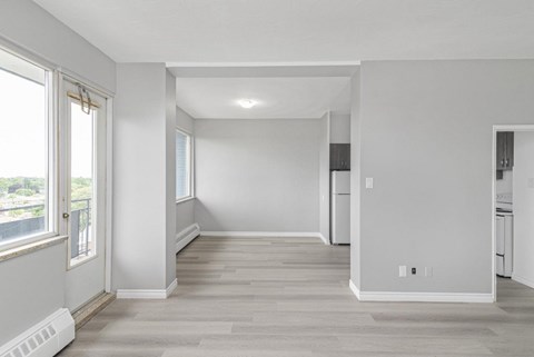 A spacious, empty room with light wood flooring and white walls.