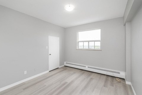 A room with a window and a radiator on the floor.