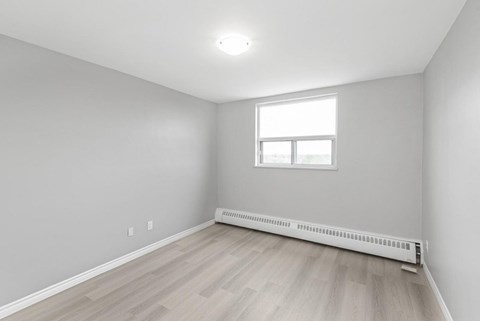 A room with a window and a radiator on the floor.