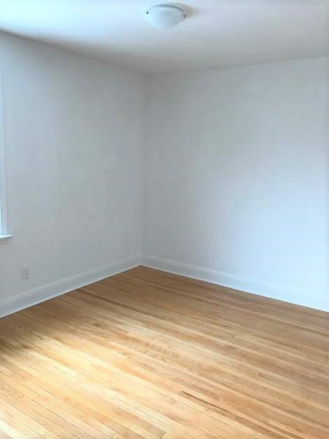 A room with wooden flooring and white walls.