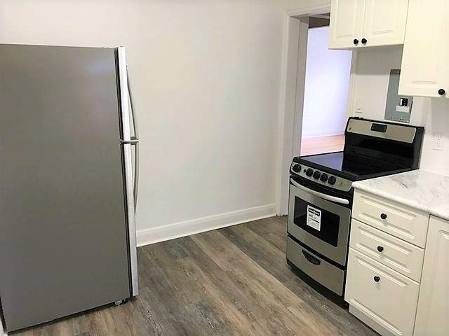 A kitchen with a refrigerator, oven, and cabinets.
