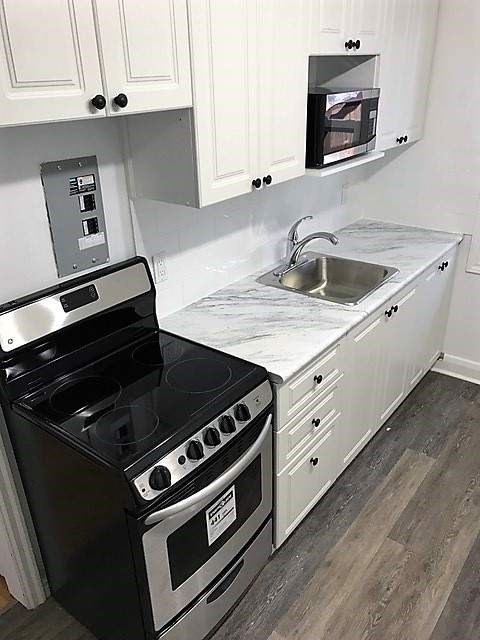 A black stove and oven in a kitchen with white cabinets.