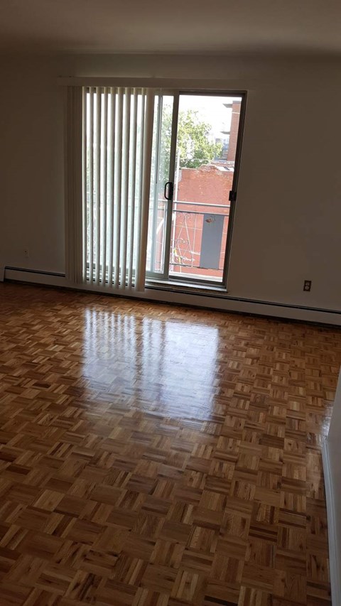 A room with a wooden floor and a window with blinds.