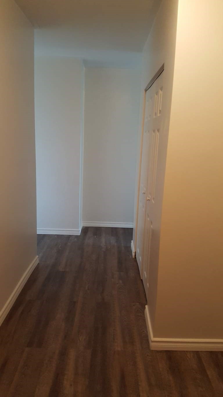 A hallway with wood floors and white walls.