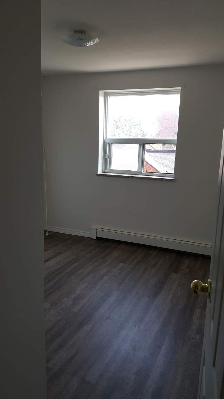 A room with a window and a wooden floor.