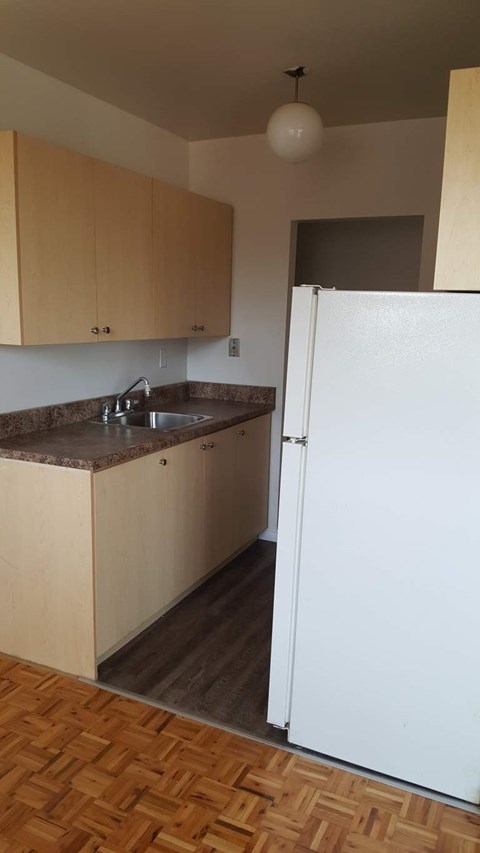 A kitchen with a white fridge and wooden cabinets.