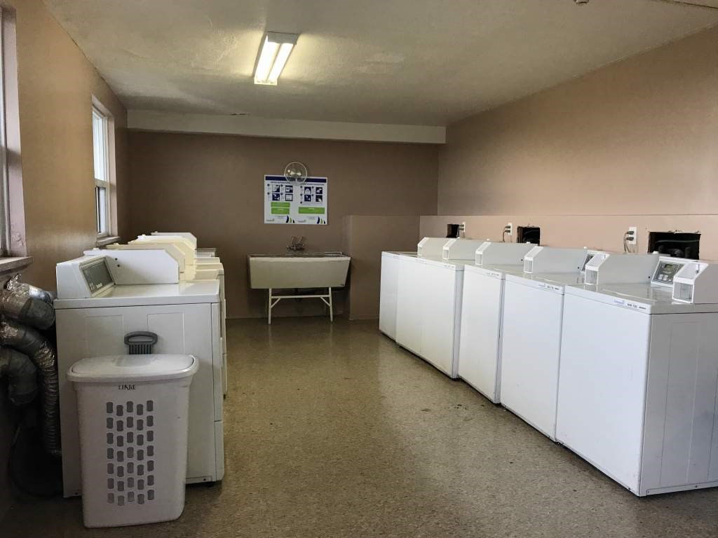 A laundry room with a white washer and dryer, a white table, and a white basket.
