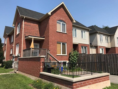 A red brick house with a black fence in front.