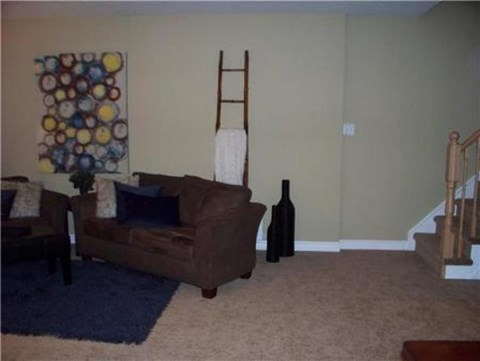 A living room with a couch, chair, and a painting on the wall.