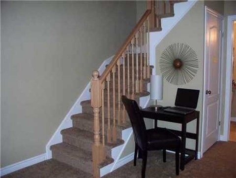 A black chair is in front of a desk with a laptop on it.