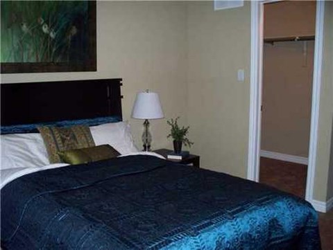 A bed with a blue blanket and a lamp on a side table.