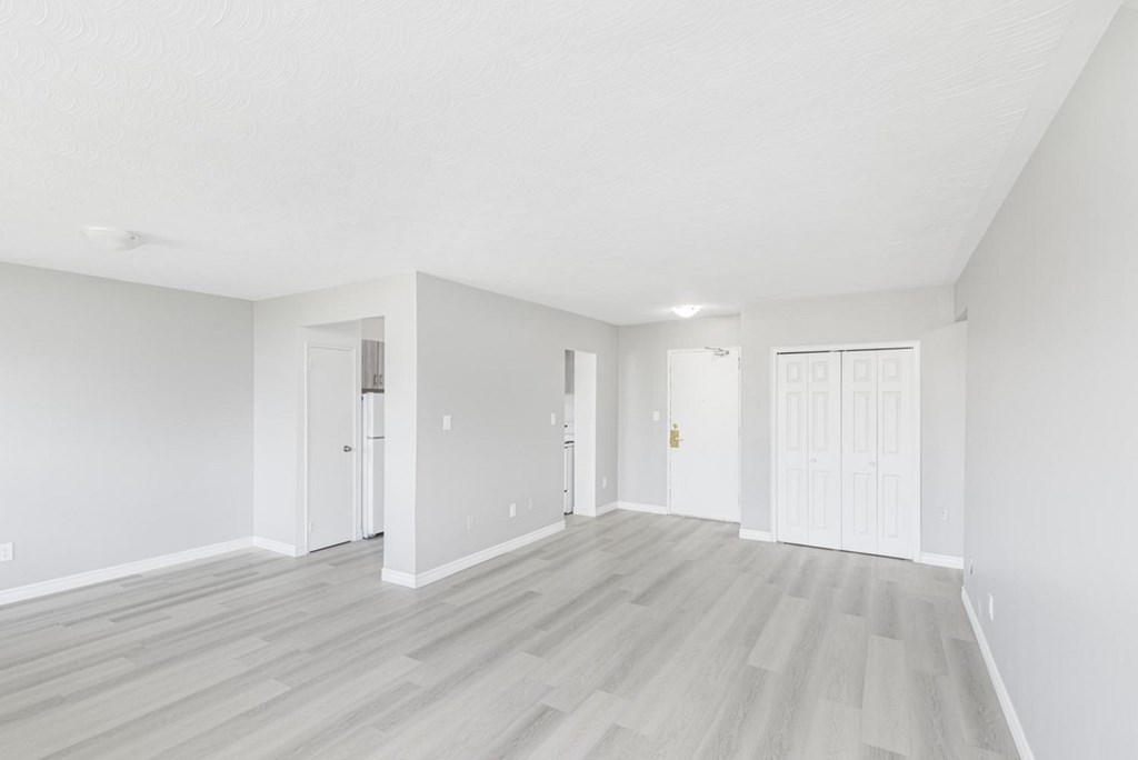 A spacious room with white walls and wooden flooring.