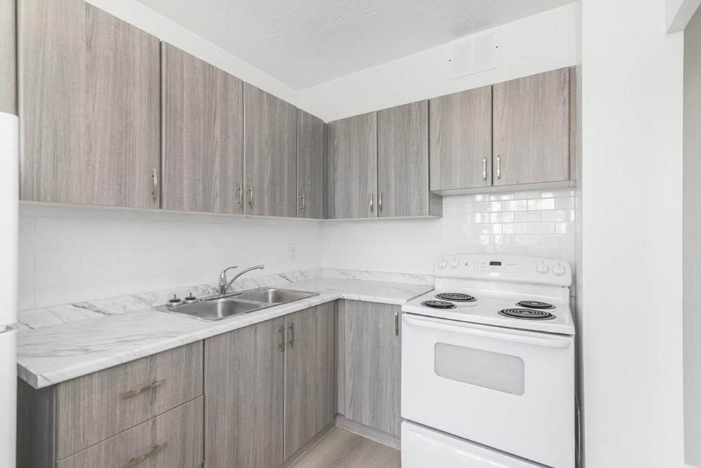 A kitchen with a white stove and sink.