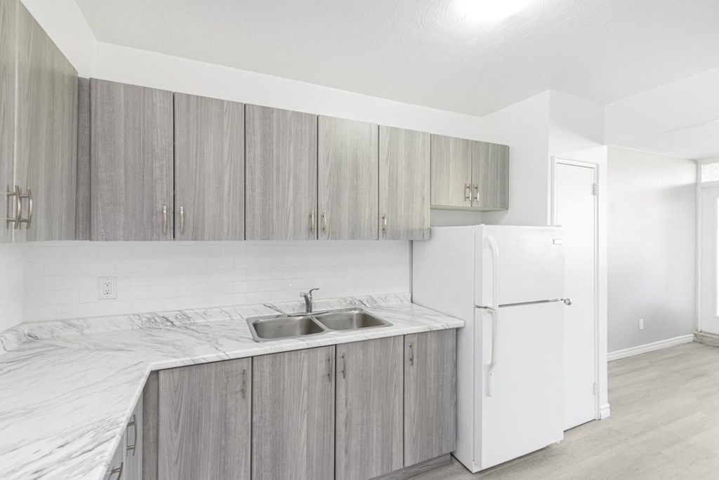 A kitchen with a white refrigerator and grey cabinets.
