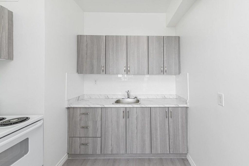 A kitchen with a white counter top and grey cabinets.