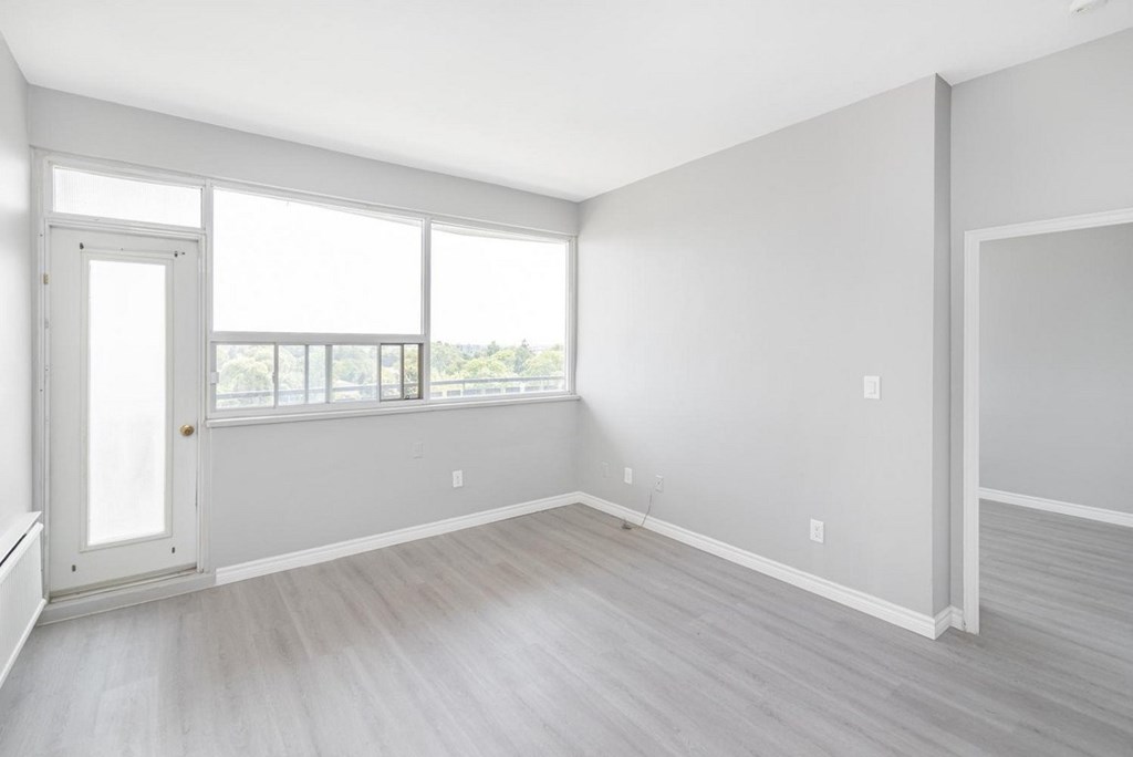 A large empty room with a door and a window.