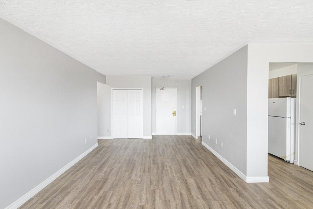 A long, empty hallway with wood flooring and white walls.