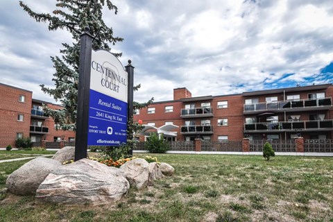 A sign for Centennial Court stands in front of apartment buildings.