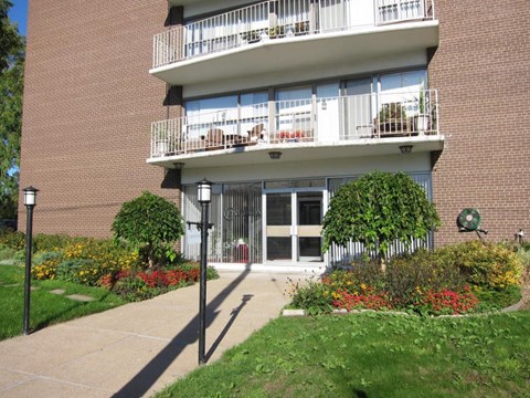 A building with a balcony and a garden in front.
