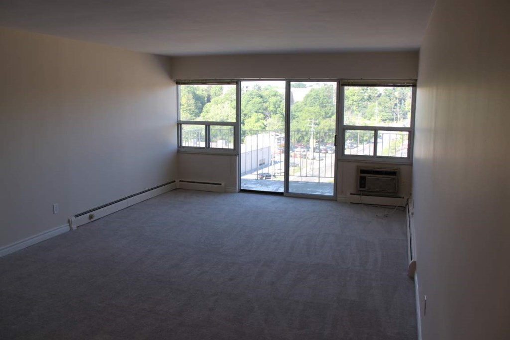 A large empty room with a fireplace and sliding glass doors.